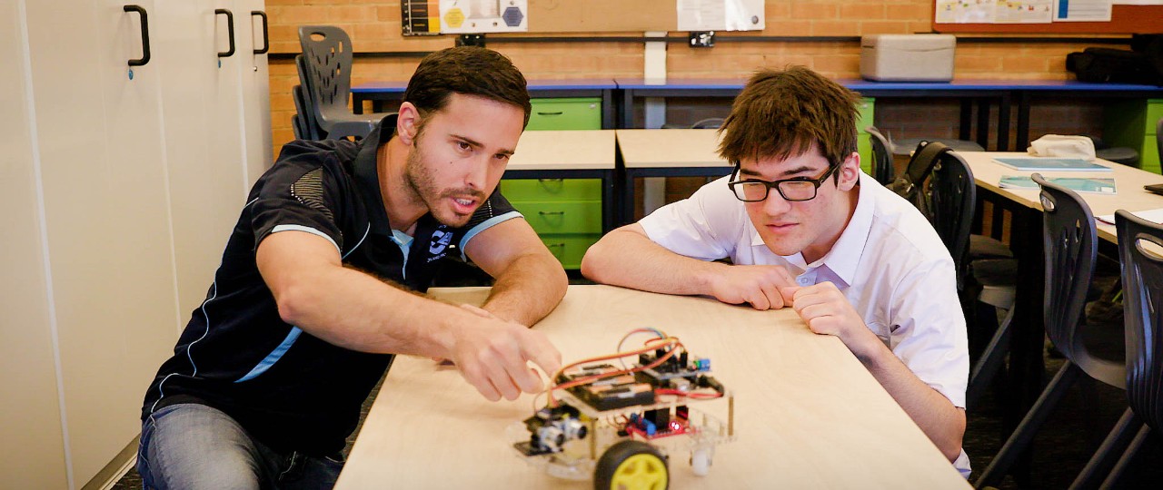 Male teacher working on project with student